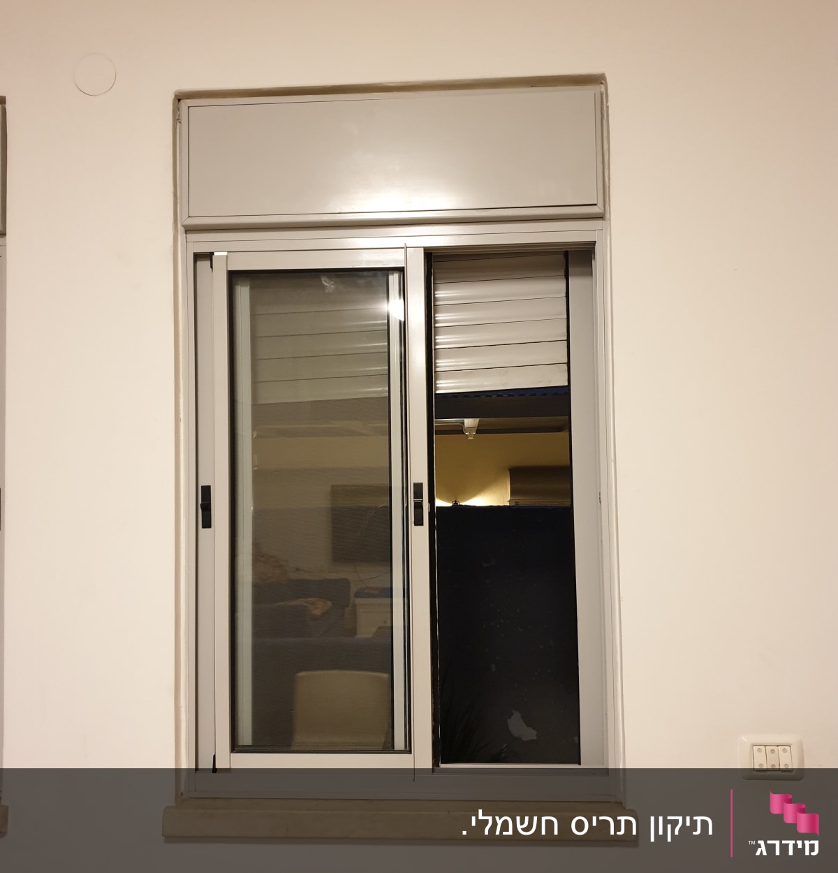 חלון עם תריסים חצי פתוחים על קיר לבן